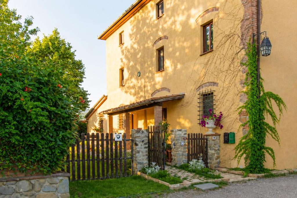 a yellow house with a fence in front of it at Agriturismo Cocò in Lamporecchio