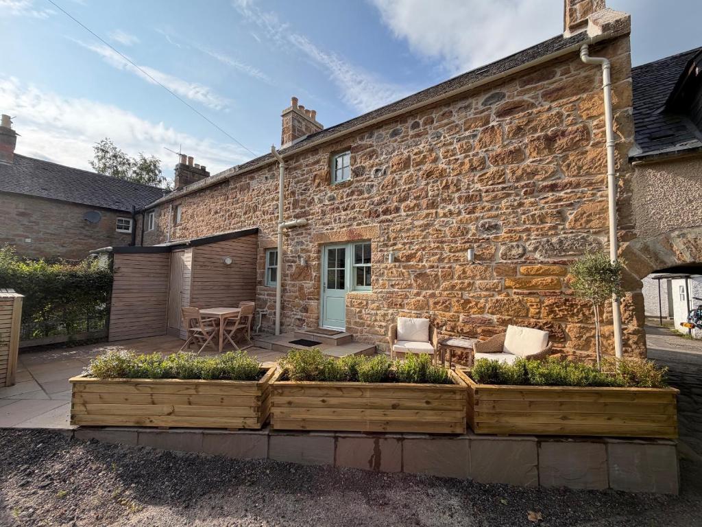 a stone house with a garden in front of it at Gilchrist Square in Dornoch