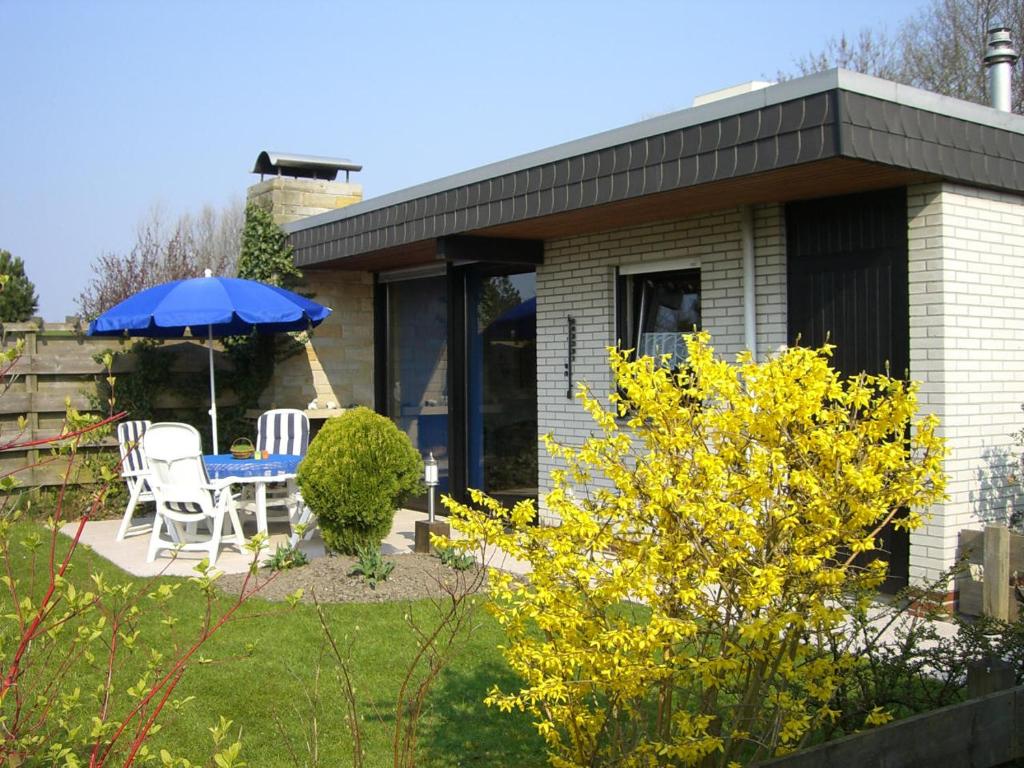 a house with a table and chairs and an umbrella at Nordseeferienbungalow in Butjadingen