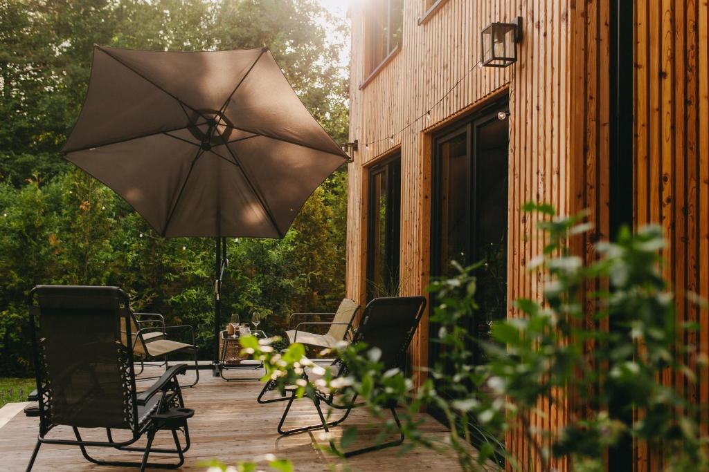 eine Terrasse mit Stühlen und einem Sonnenschirm auf einem Deck in der Unterkunft Otuli in Ćmińsk