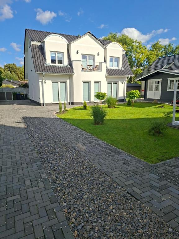 a large white house with a cobblestone driveway at Apartment Villa Brieselang in Brieselang