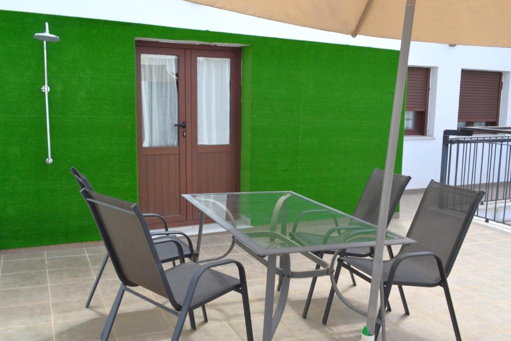 a table and chairs with a green wall at Apartamentos Cruz Conde in Córdoba