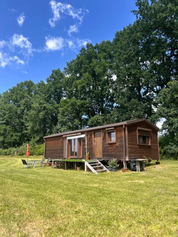 a wooden cabin in a field with trees in the background at Luční domek in Protivín