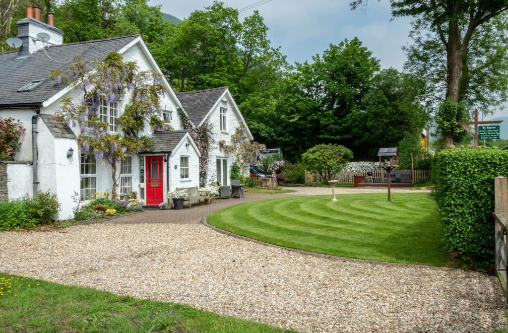 a house with a red door and a gravel driveway at Ty Derw B & B in Dinas Mawddwy