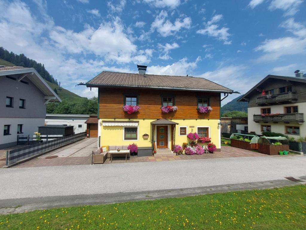 a yellow house with flowers on the front at Ferienwohnung Kasbacher in Bruck an der Großglocknerstraße