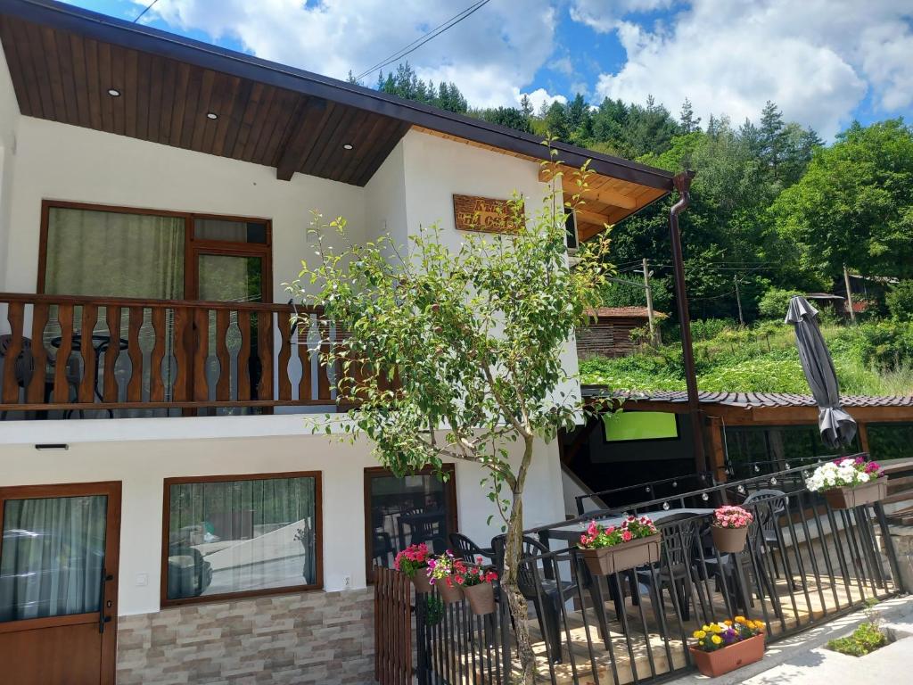 a house with a balcony and a table and chairs at Къща за гости "НА СЕЛО" Грохотно in Devin