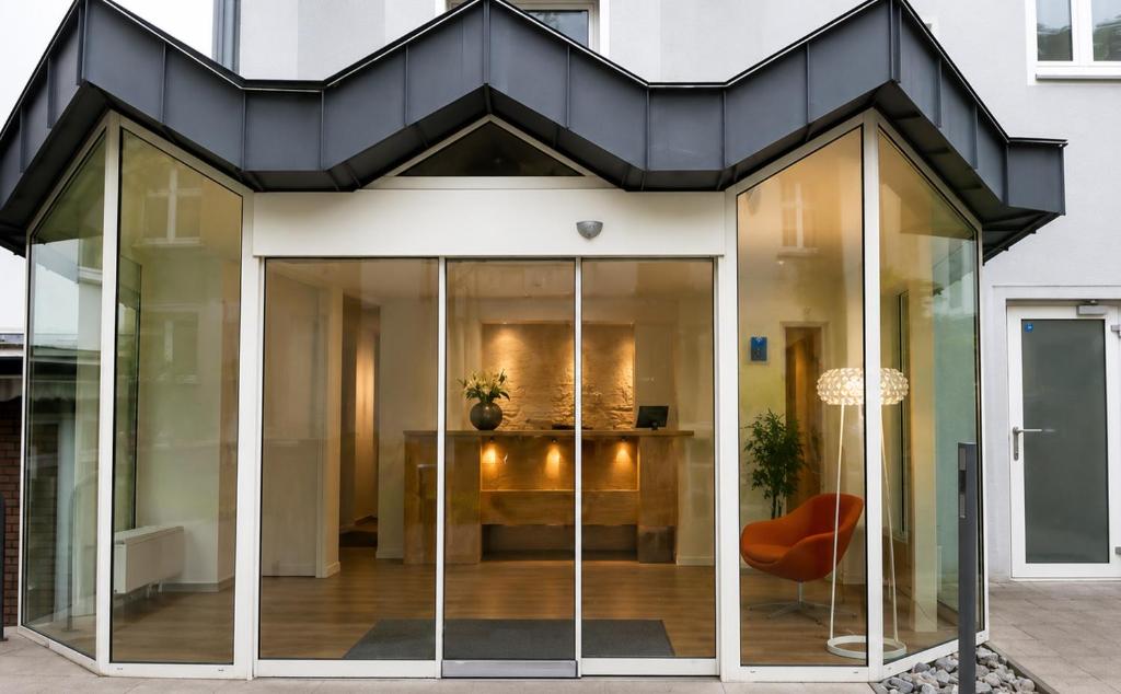a glass extension of a house with a black roof at DORMERO Hotel Essen in Essen