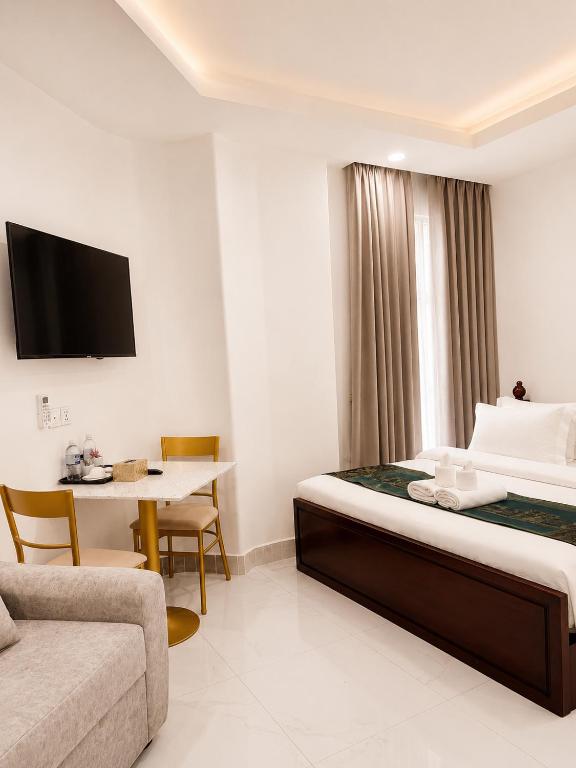 a hotel room with a bed and a table and a couch at Try Residence, The Elysée Koh Pich in Phnom Penh