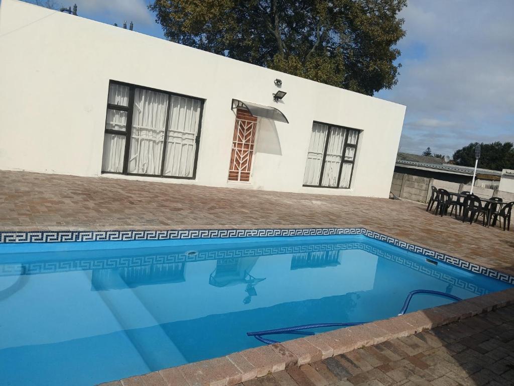 a villa with a swimming pool in front of a house at Stay at Gabby's- no loadshedding in Cape Town