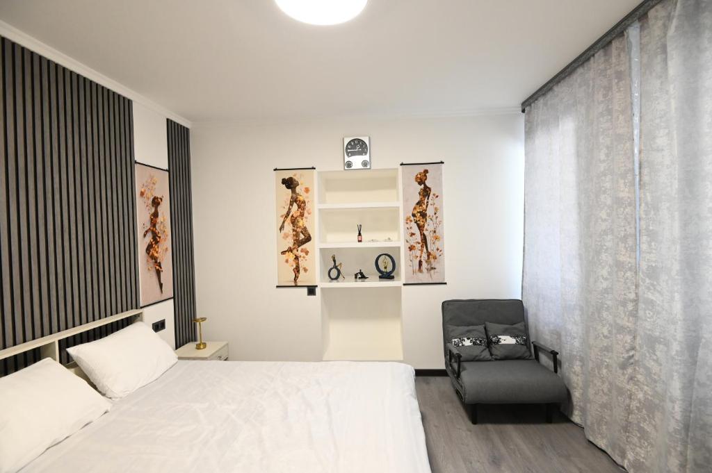 a white bedroom with a bed and a chair at Jivani 105 in Gyumri