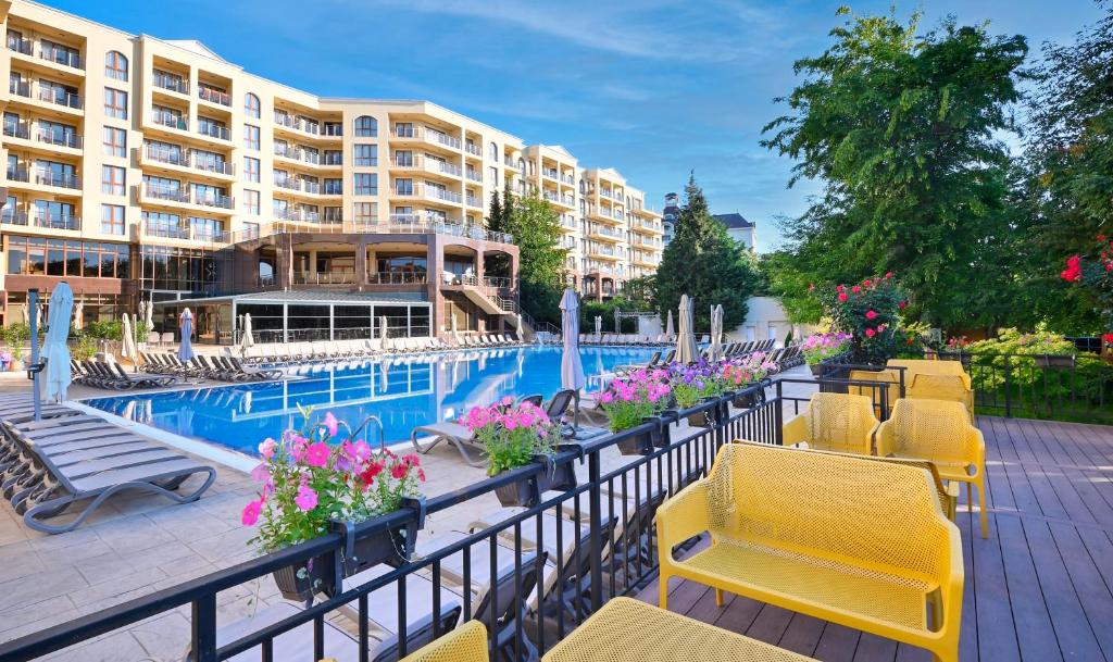 a resort with a pool and chairs and a building at Apart Hotel Golden Line in Golden Sands
