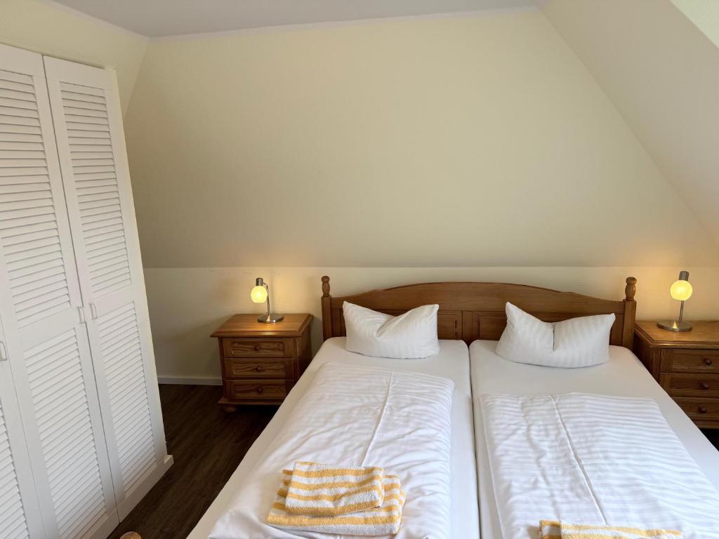 una camera da letto con due letti e due comodini di Hotel Schatthaus a Greetsiel