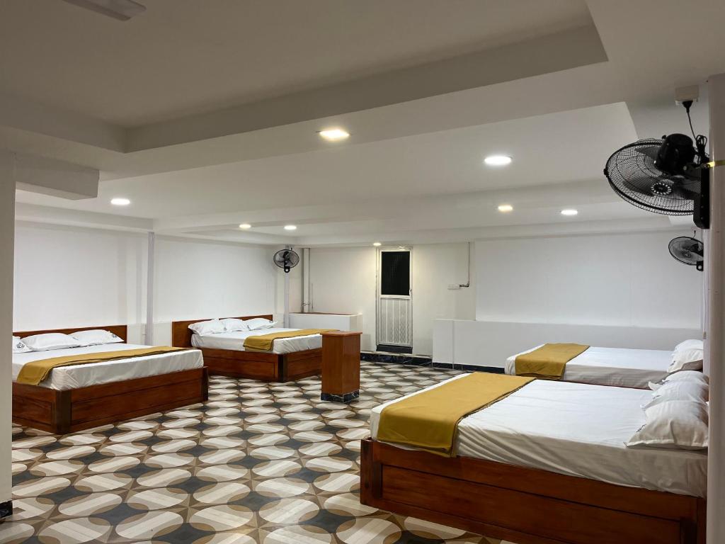 a hotel room with three beds in a room at nkm cottage in Rāmeswaram