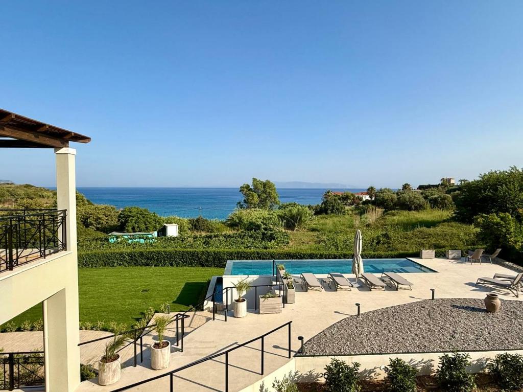 a resort with a swimming pool and the ocean at Filon Ktima Beachfront Upscale Villa in Karavádhos
