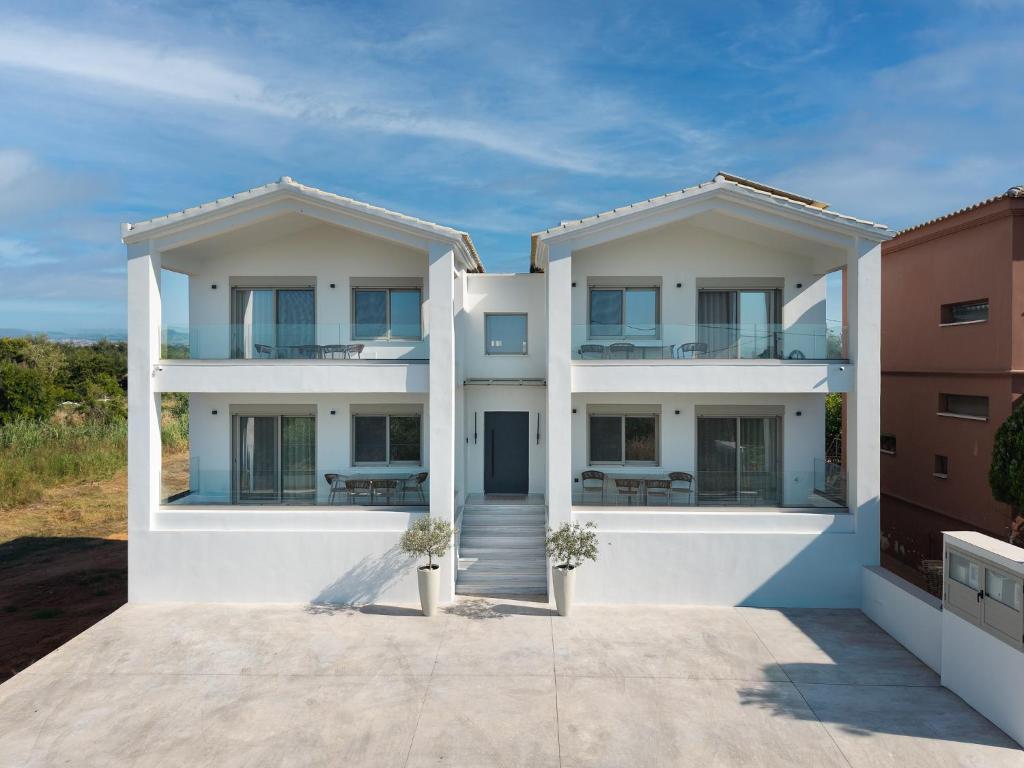 a white apartment building with two balconies at Kleopatra Homes - Napoleontos in Messini