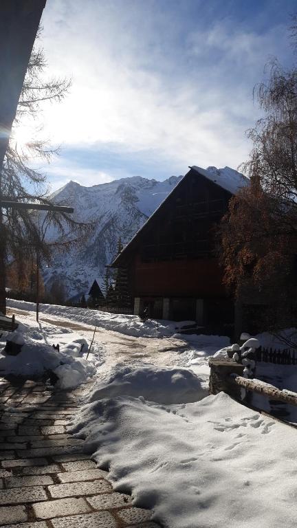 a snow covered yard with a building with mountains in the background at Luxury Lodges by Grand Hotel Sitea in Sestriere