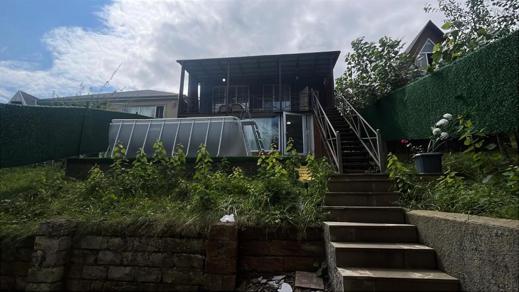 ein Haus mit Treppe, die zu einem Haus hinaufführt in der Unterkunft Ромашка in Uçgün