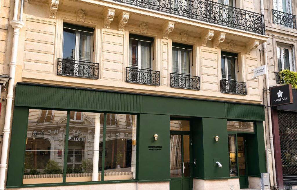 a building with a green facade and windows at Alfred Hotels Paris Gare du Nord- Hôtel Rénové in Paris