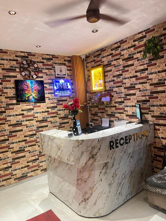 a reception desk in a lobby with a brick wall at JMB HOTEL Height in Indore
