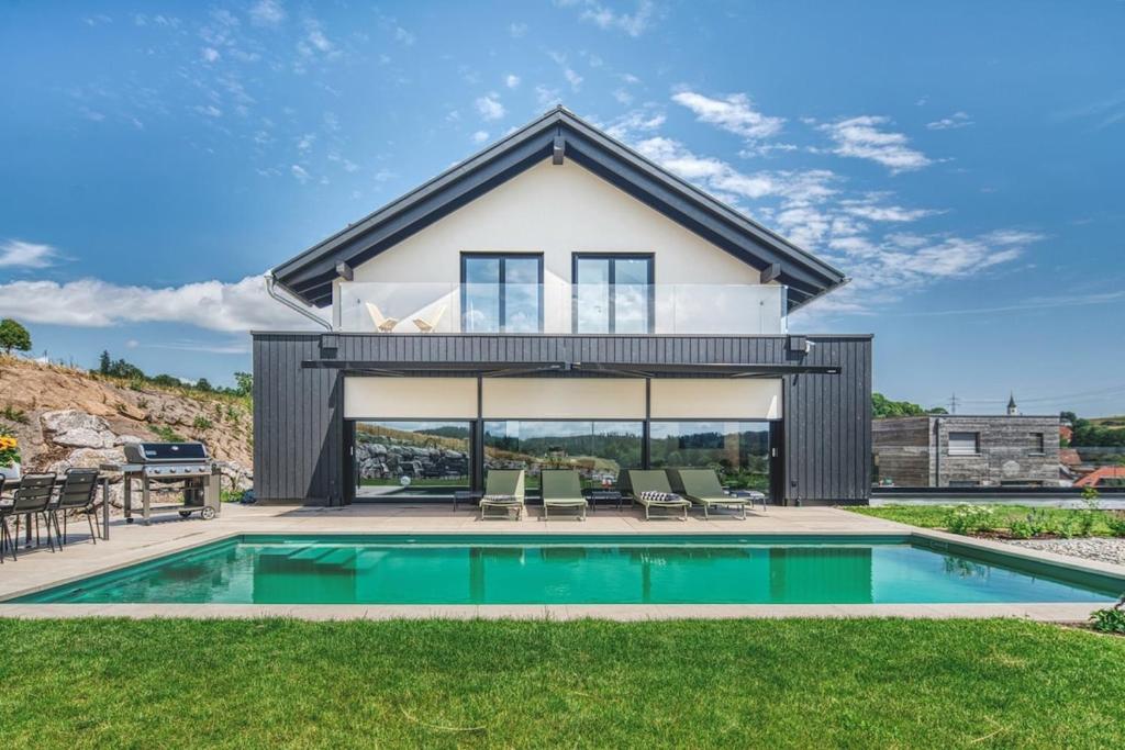 a home with a swimming pool and a house at BlackForestChillOut - Pool - Garten - BBQ - Sauna in Stühlingen