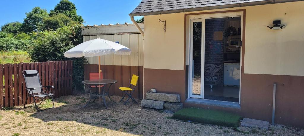 a patio with a table and an umbrella next to a house at Guim appart in Guimiliau