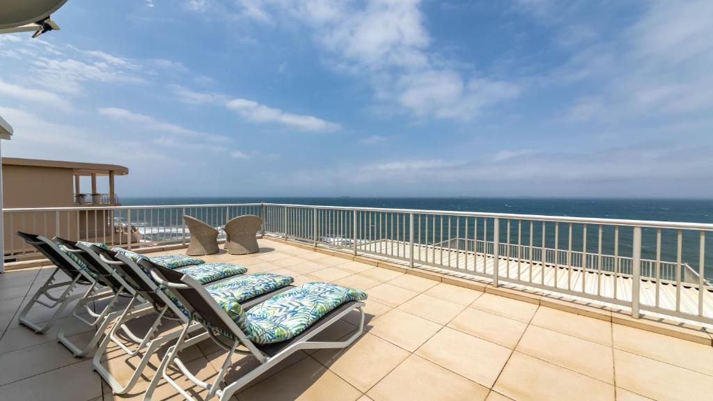a balcony with chairs and a view of the ocean at 62 Camarque Umdloti Beachfront in Umdloti