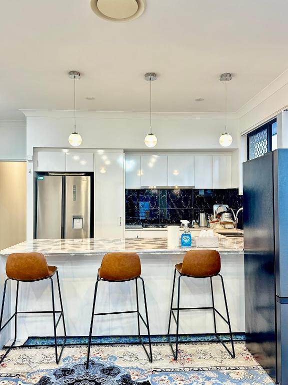 a kitchen with two stools at a kitchen counter at Noble place in Loganlea in Loganlea