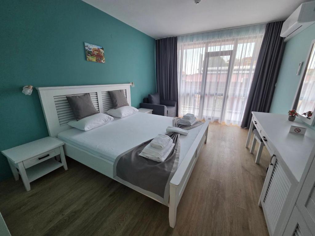 a bedroom with a bed with a blue wall at Хотел Калитеа in Pomorie