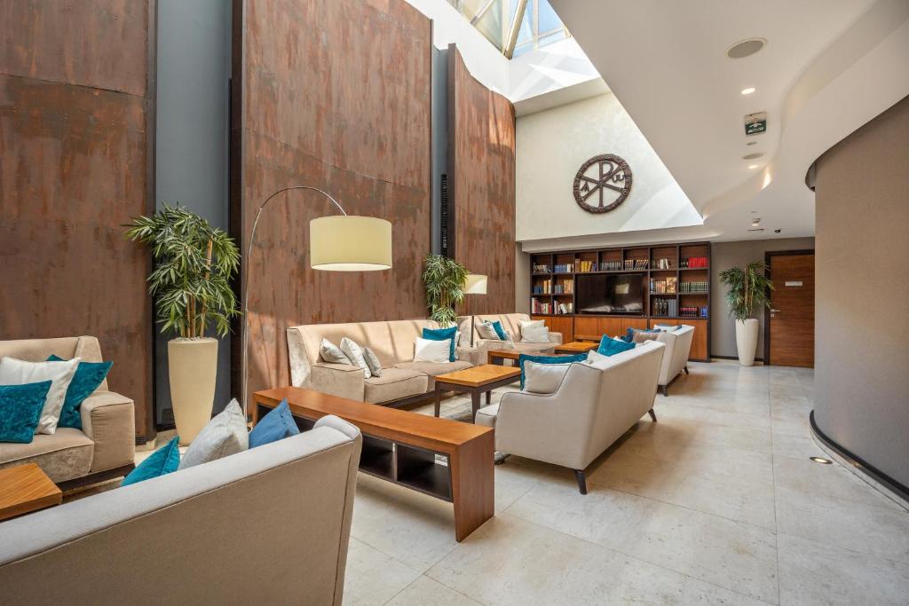 a lobby with couches and tables and a clock at Hotel Constantine the Great in Belgrade