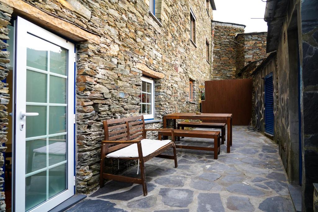 a patio with two wooden chairs and a table at Casas Martinho - Algares in Piódão