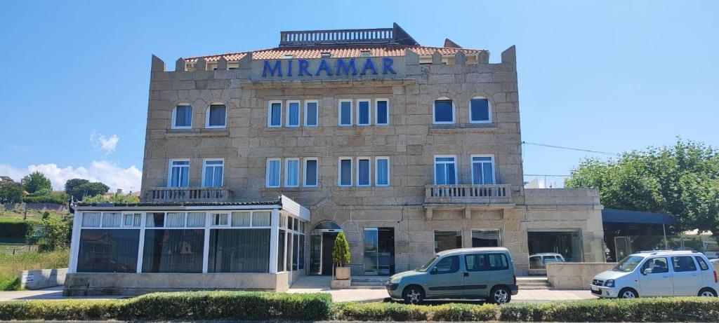 a building with two cars parked in front of it at Hotel Miramar Playa America Nigran in Nigrán