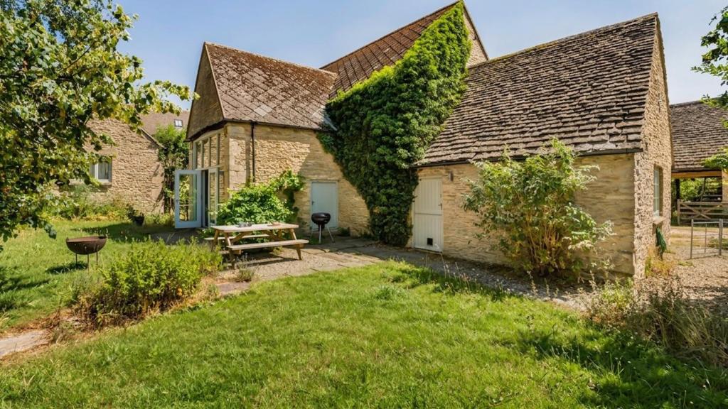 an old stone house with ivy growing on it at Butts Farm in Cirencester