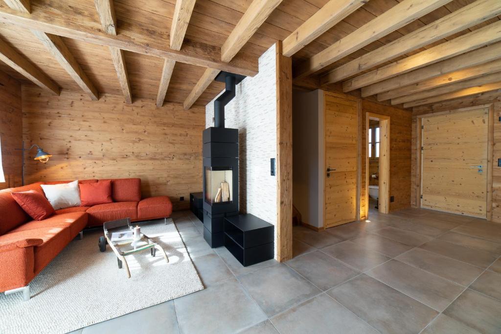 a living room with a red couch and a fireplace at Chalet Brisi - Luxury & Bergblick in Wildhaus