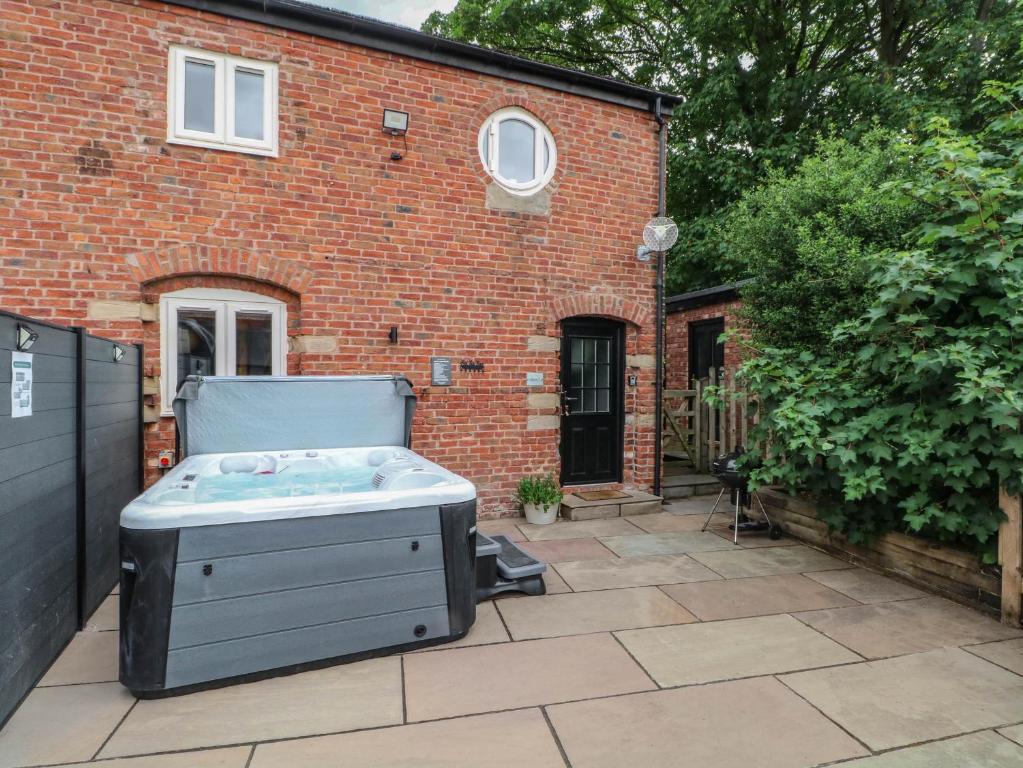 a hot tub in the backyard of a brick building at Barn 2 in Sandbach