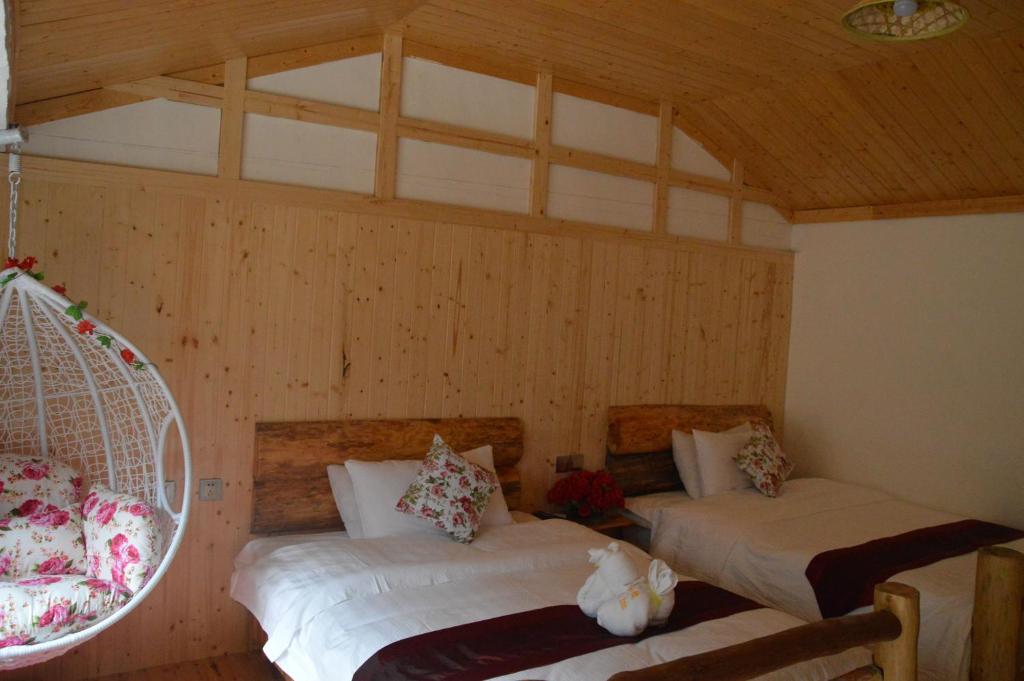 two beds in a room with wooden walls at Yangjiajie Inn in Zhangjiajie