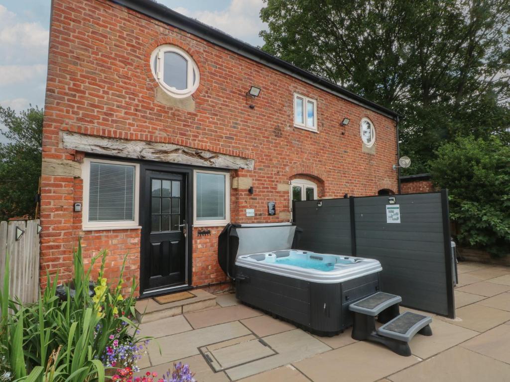 a bath tub in front of a brick house at Barn 1 in Sandbach