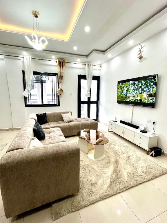 a living room with a large couch and a tv at Western Suites in Douala
