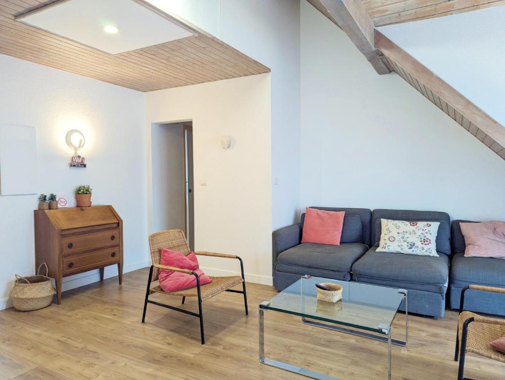 a living room with a blue couch and a glass table at L'Hirondelle - Charming flat - in Blotzheim