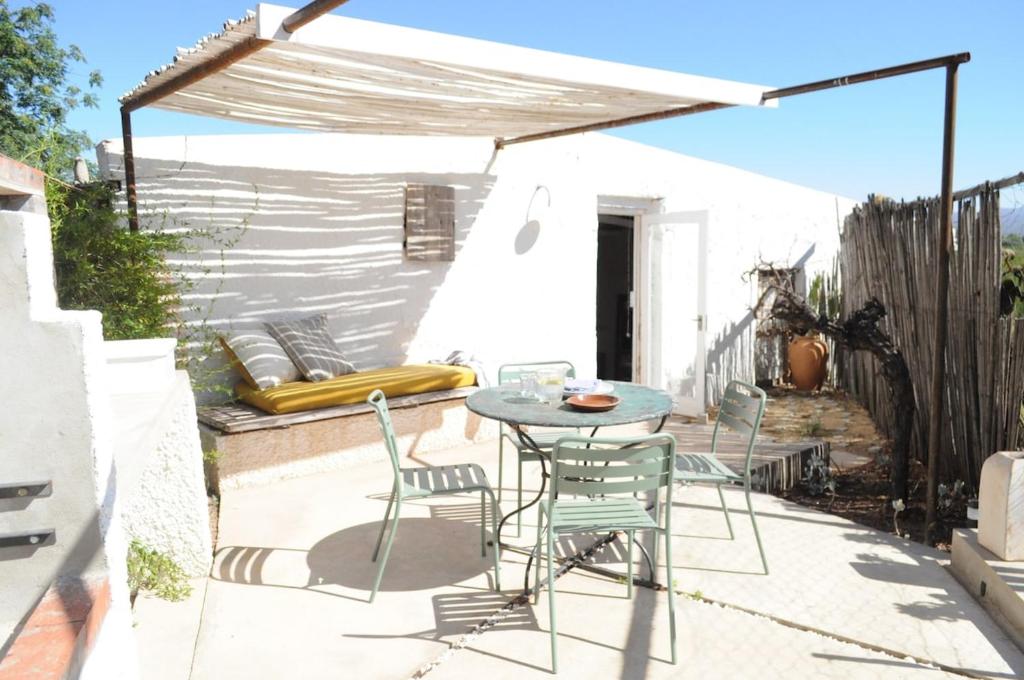 a patio with a table and chairs under a canopy at De Waenhuis Cottage in Calitzdorp
