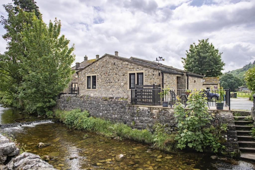 a stone house next to a river at The Smithy in Kettlewell