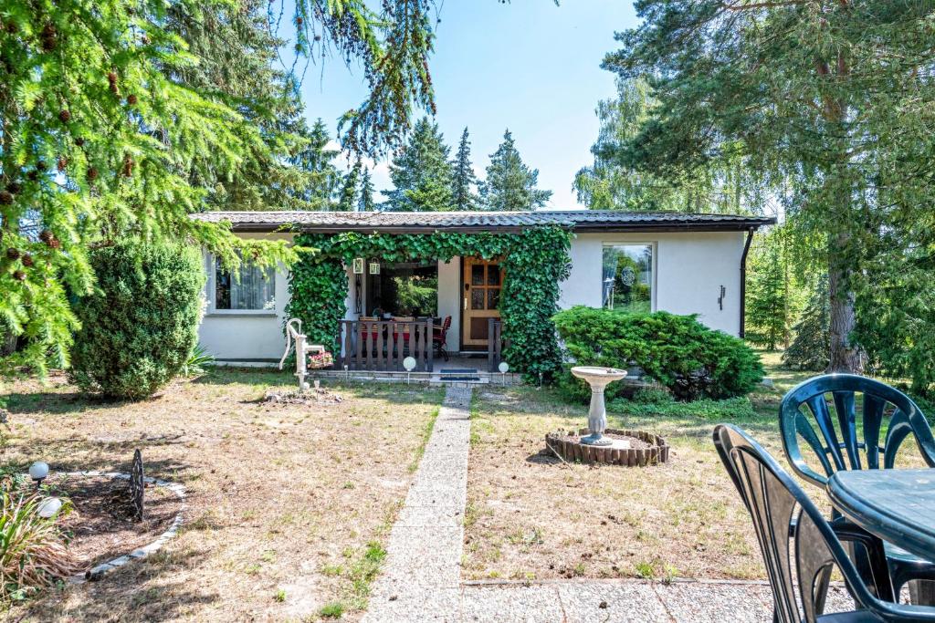 a small cottage with a table and chairs in a yard at Bungalow an der Havel in Margarethenhof