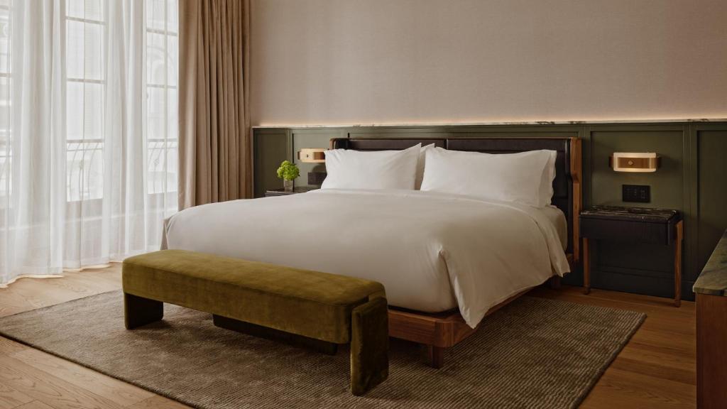 a bedroom with a large white bed with a bench at Hotel Nelligan in Montreal