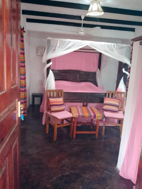 a bedroom with two chairs and a bed with a canopy at Al Mar Bed and Breakfast in Watamu