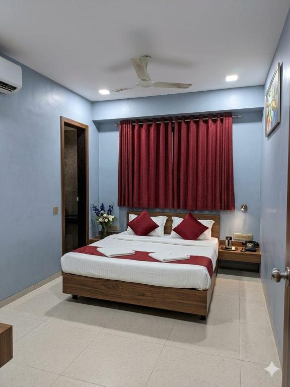 a bedroom with a bed with a red curtain at Hotel Happinex Inn in Surat