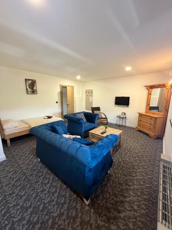 a living room with a blue couch and a bed at Motel Anić in Novi Travnik