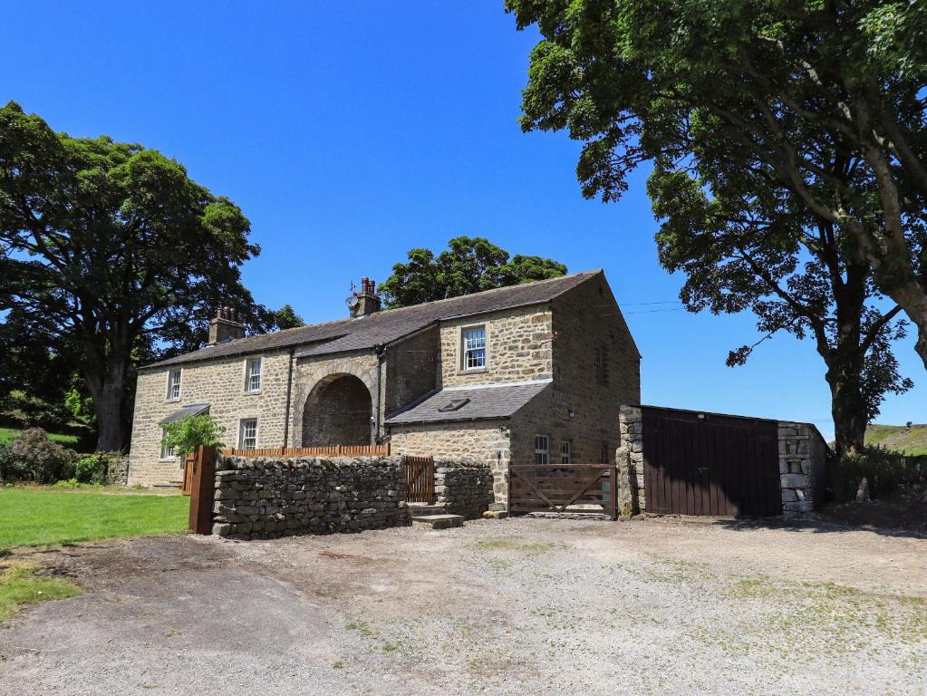 an old stone barn with a fence in front of it at Ragged Hall Barn in Settle