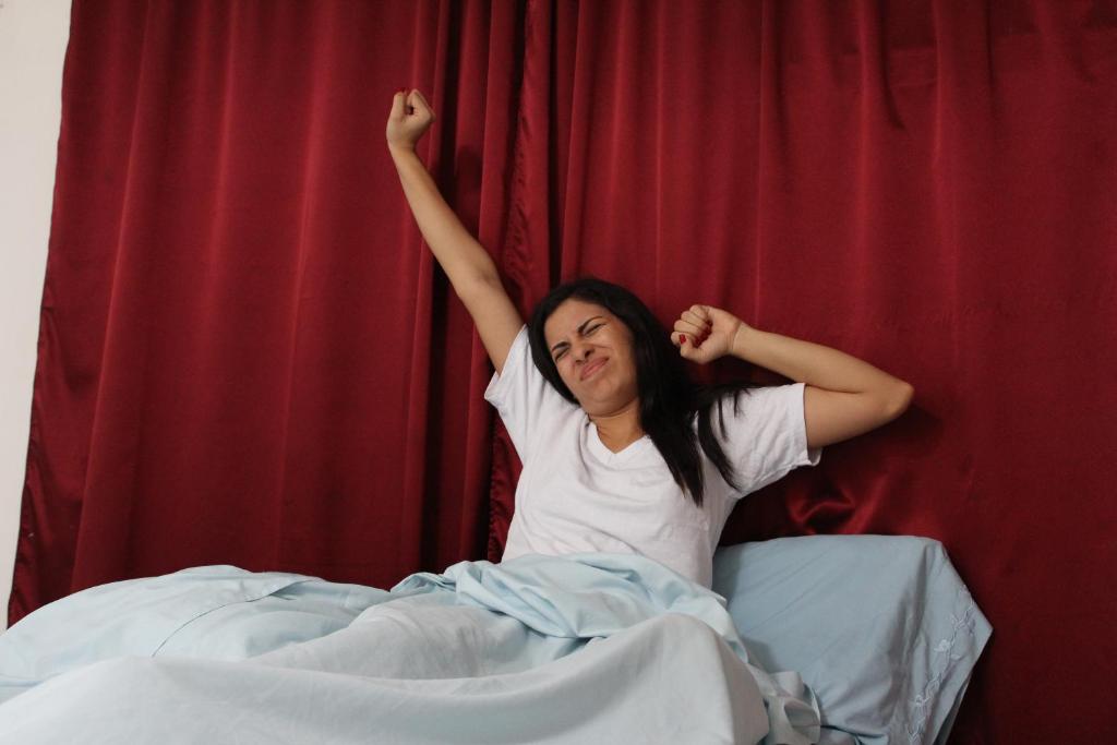 a woman laying in bed with her arms in the air at El Callejon Guest House in León