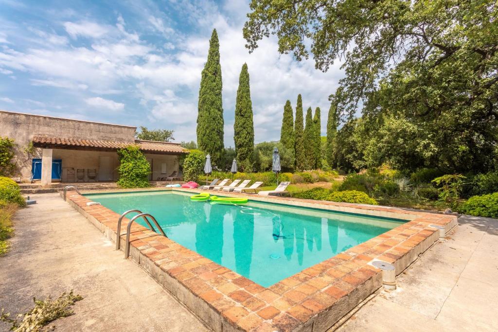 an outdoor swimming pool with a brick wall and trees at Grand mas provencal in La Farlède