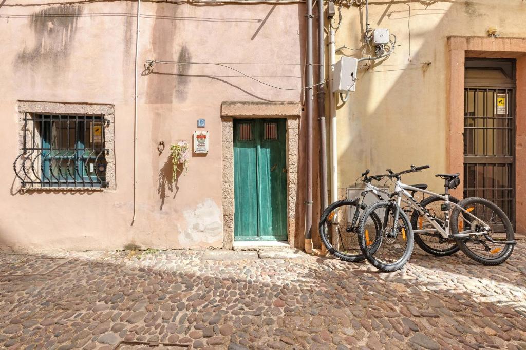 two bikes parked next to a building with a green door at Romeo e Giulietta Rooms in Bosa