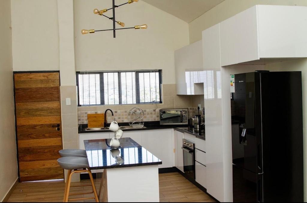 a kitchen with a black refrigerator and a counter at Ultimate Lotus in Manzini